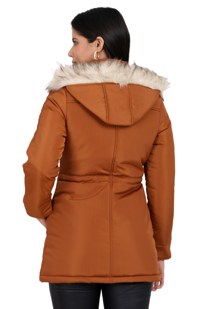 A back pose of a standing woman, wearing Coatsnmore’s rust quilted parka jacket with a removable hood, quilted pattern and black jeans.