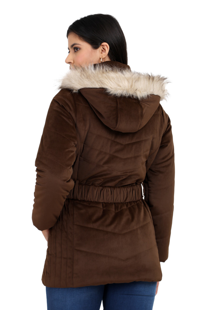 The back view of a standing woman wearing Coatsnmore’s coffee velvet quilted jacket with a removable hood and adjustable waistband paired with blue jeans.