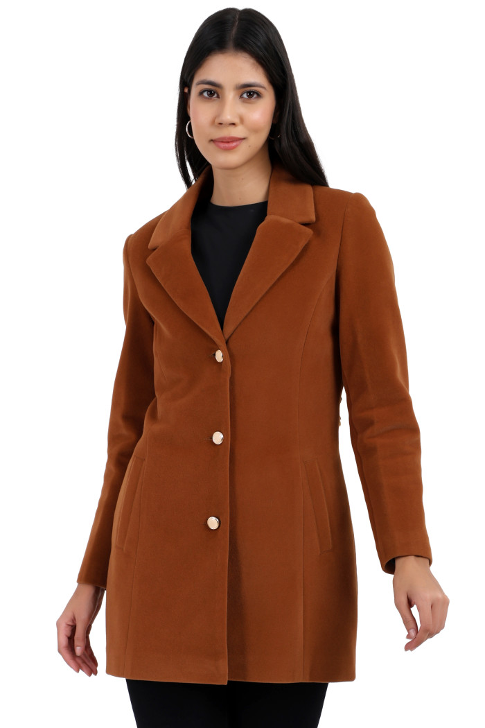 A woman is giving a standing side pose, wearing Coatsnmore’s rust Semi-Long Velvet coat with a lapel collar, button closure, side pockets and black jeans.