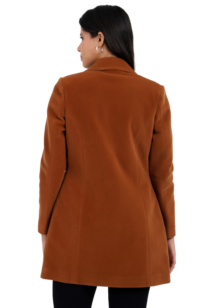 A back pose of a standing woman, wearing Coatsnmore’s rust Semi-Long Velvet coat with a lapel collar, button closure, side pockets and black jeans.