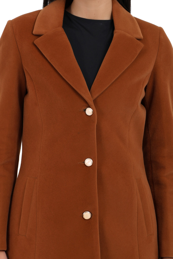 A woman in a cropped image is wearing Coatsnmore’s rust Semi-Long Velvet coat with a lapel collar, button closure and side pockets.