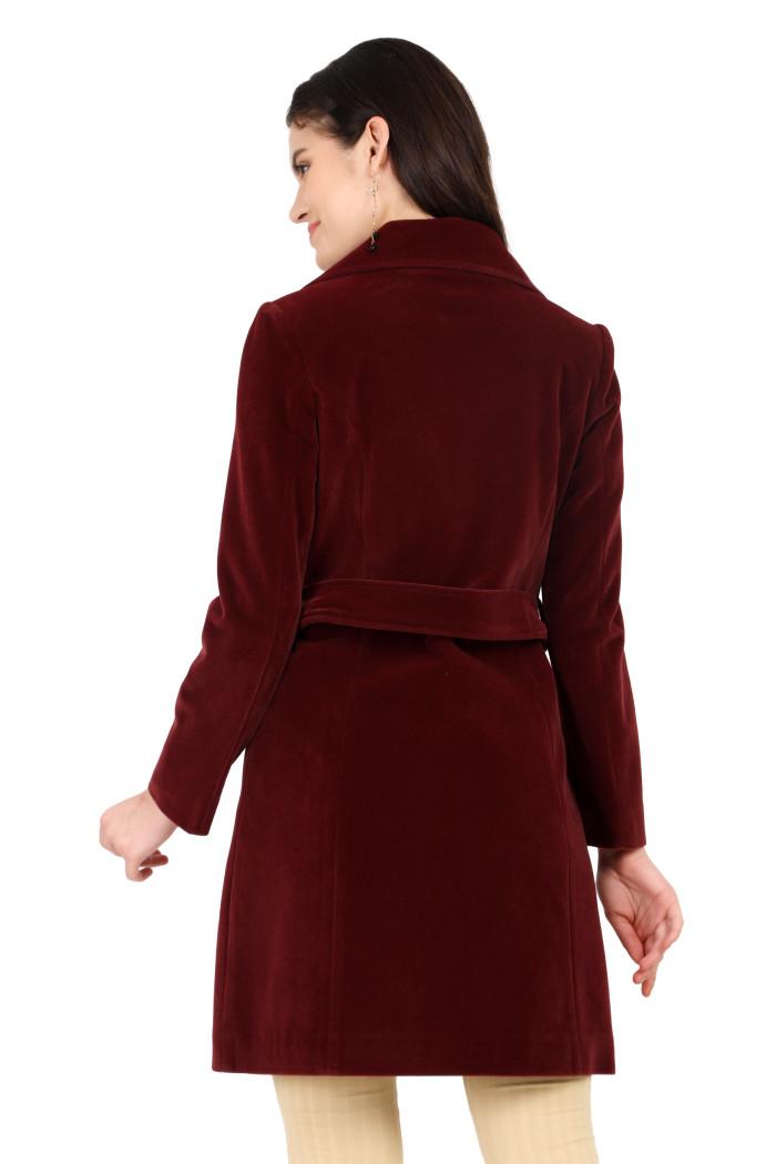 A back pose of a standing woman, wearing Trufit’s Long wine Velvet coat with a lapel collar, button closure, belt, side pockets and skin bell bottom.