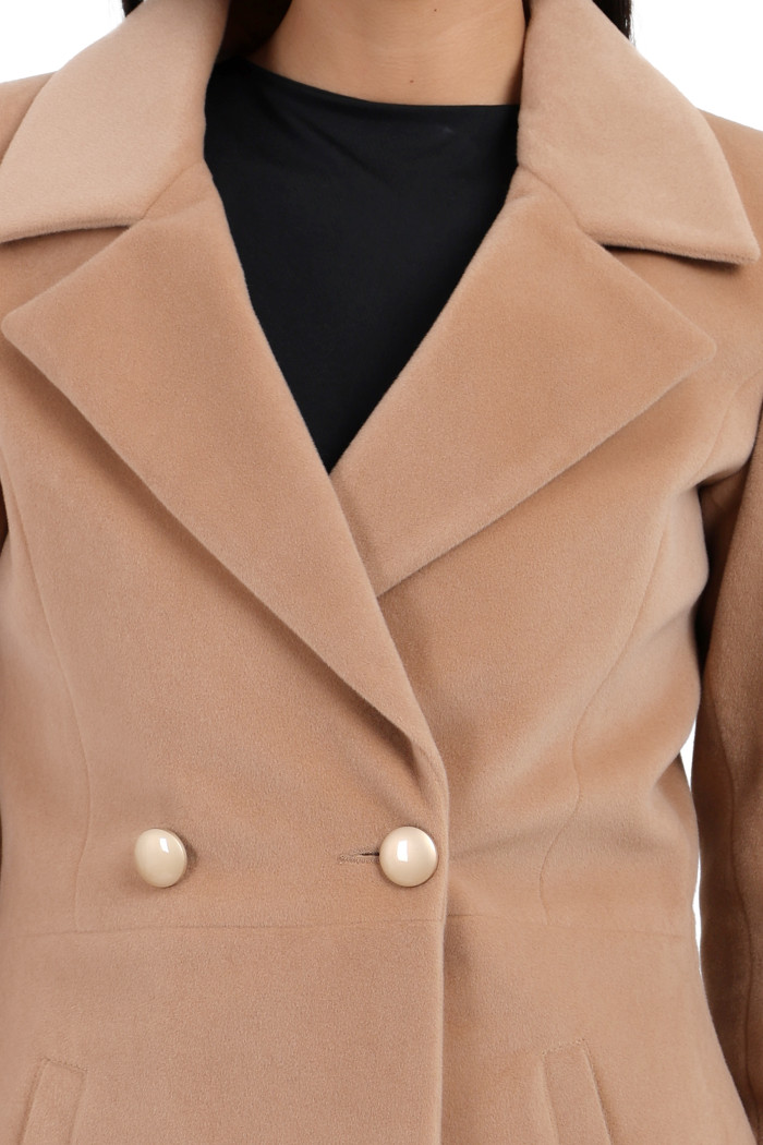 A cropped shot of a woman wearing Trufit’s Double Breasted velvet coat in camel colour with a lapel collar, side pockets and a button closure.