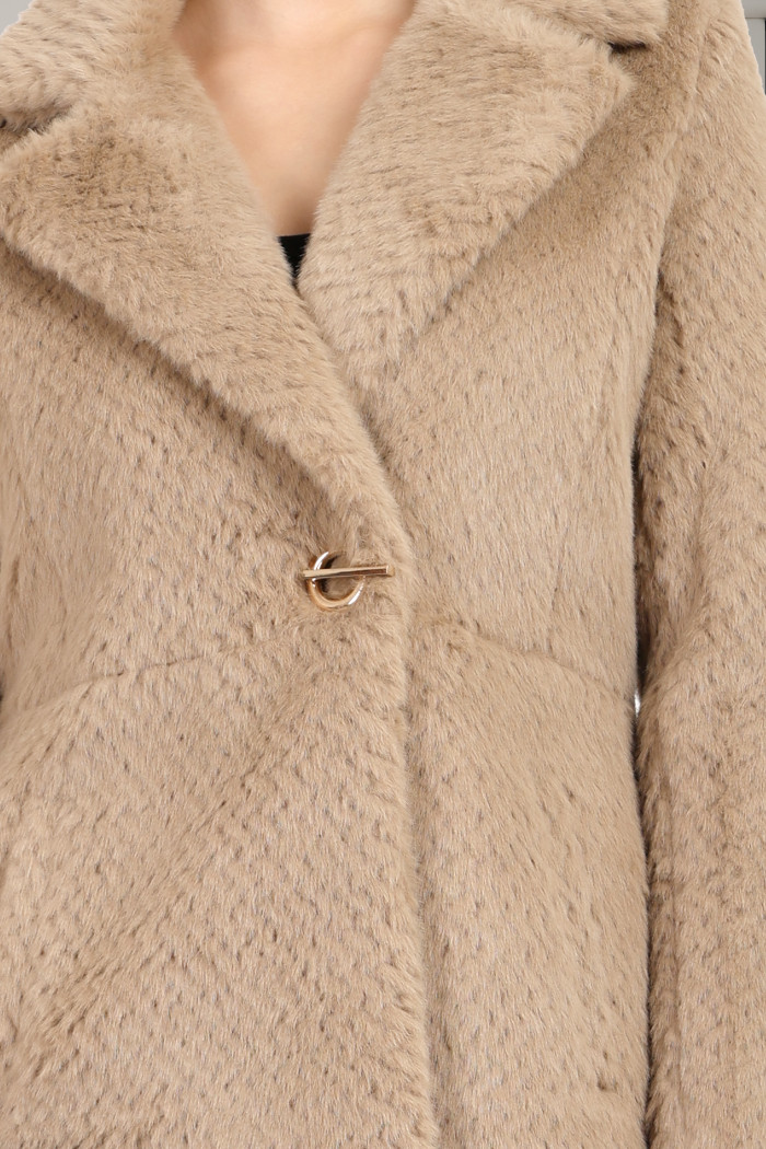 A woman in a cropped image is wearing Coatsnmore’s beige double-breast Semi-Long coat with a lapel collar, button closure and side pockets.