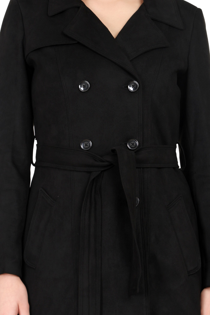 A woman in a cropped image is wearing Coatsnmore’s black double-breasted trench coat with a lapel collar, button closure, a belt and side pockets.