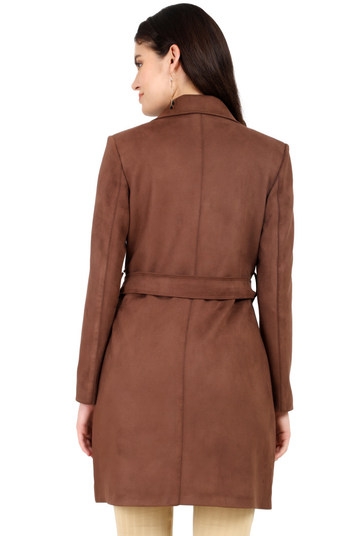 A back pose of a standing woman wearing Coatsnmore’s coffee double-breasted trench coat with a belt and skin bell bottom.