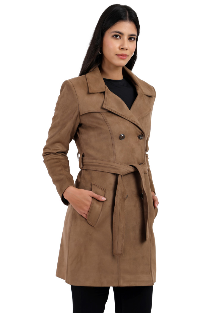 A woman is holding a standing side pose, wearing Coatsnmore’s mouse double-breasted trench coat with a lapel collar, button closure, belt, side pockets, and black bottom with her hands in the pocket.