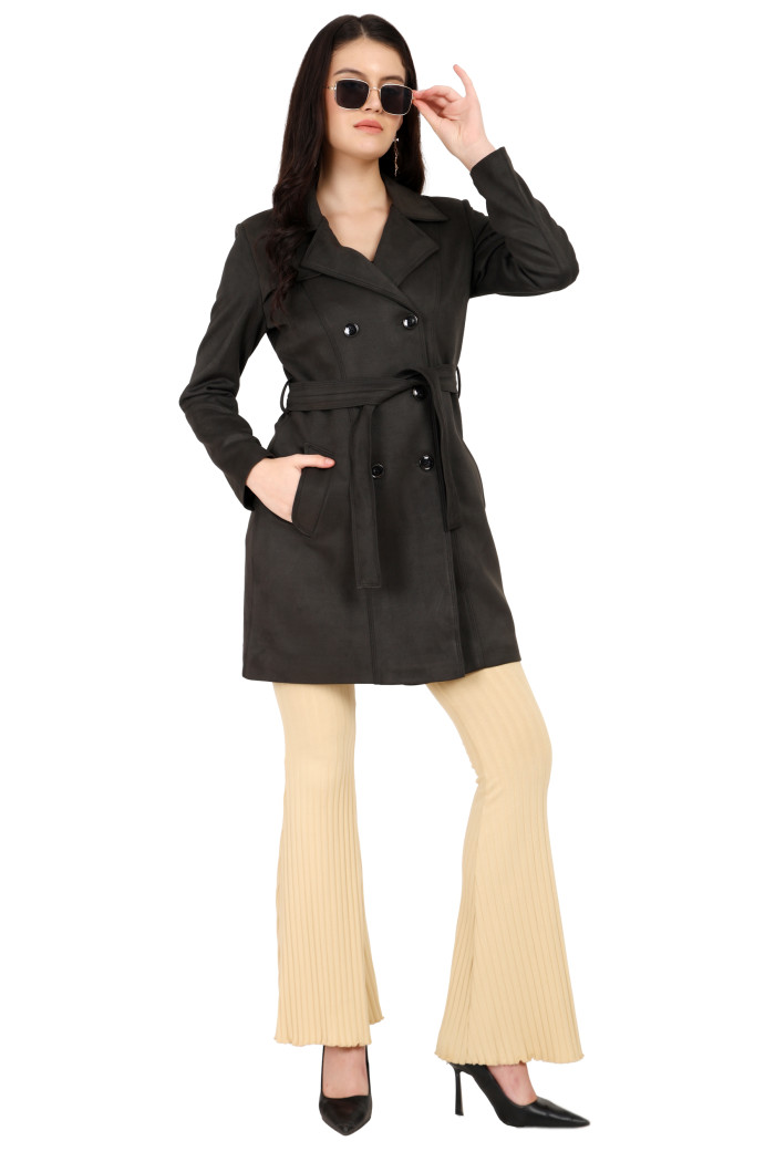 A woman is giving a standing side pose in black shades, wearing Coatsnmore’s olive double-breast trench coat with a lapel collar, button closure, a belt, side pockets and bottoms and holding shades from her left hand and right hand in a pocket.