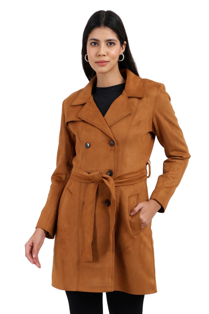 A woman in a standing pose, wearing shades, Coatsnmore’s tan double-breasted trench coat with a lapel collar, button closure, belt, side pockets, and black bottom, with her left hand in the pocket.