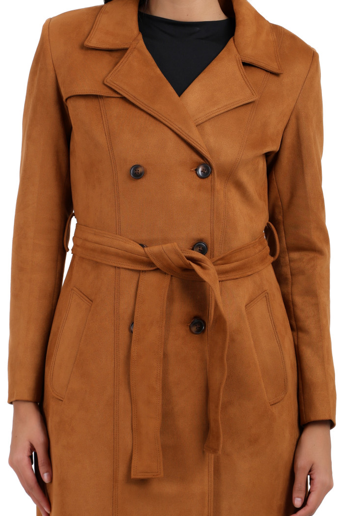 A woman in a cropped image is wearing Coatsnmore’s tan double-breast trench coat with a lapel collar, button closure, belt and side pockets.