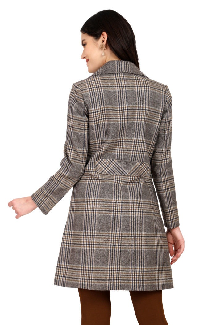 A back pose of a standing woman, wearing Trufit’s brown double breast woolen tweed long coat with a lapel collar and brown jeans.