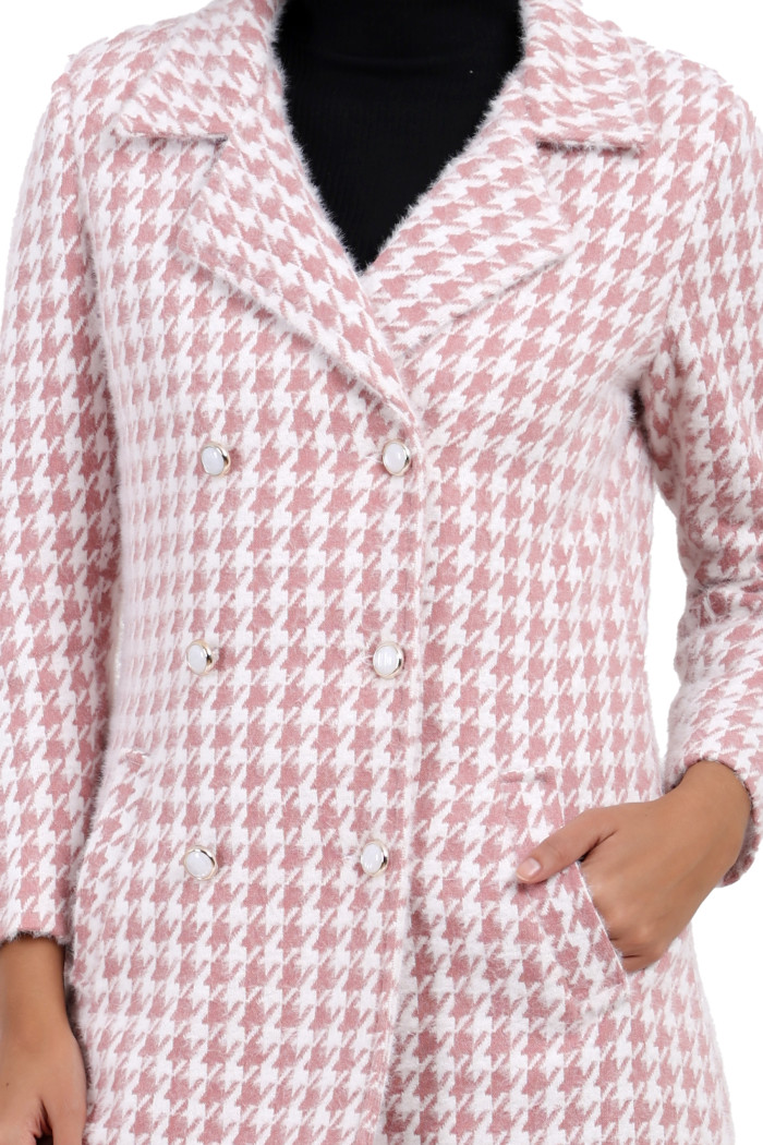 A cropped frame captures a woman dressed in Coatsnmore’s pink double-breasted semi-long coat featuring a lapel collar, button-up design and side pockets with her left hand in the pocket.