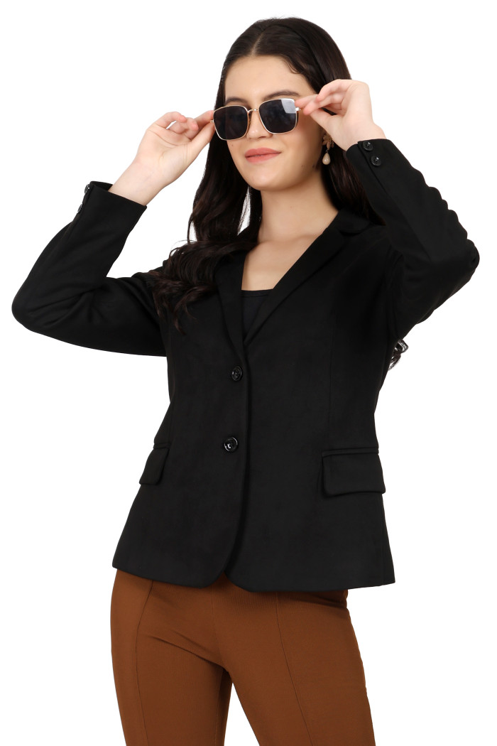 A standing pose of a woman wearing Trufit’s black short-length coat with a lapel collar, side pockets, and a button closure styled in brown jeans while holding her shades from her hand.