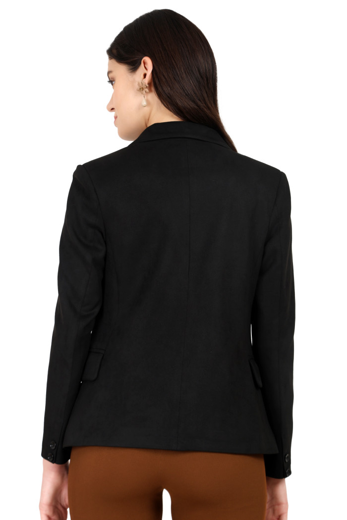 A back pose of a standing woman wearing Trufit’s black short-length coat with a lapel collar and brown jeans.