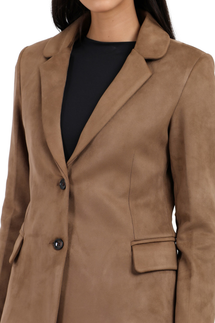 A cropped shot of a woman wearing Trufit’s short-length coat in olive with a lapel collar, side pockets and a button closure while holding her hands.