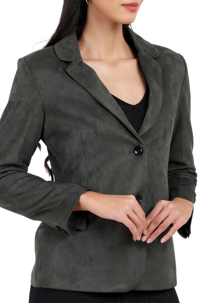 A cropped shot of a woman wearing Trufit’s short-length coat in olive with a lapel collar, side pockets and a button closure while holding her hands.