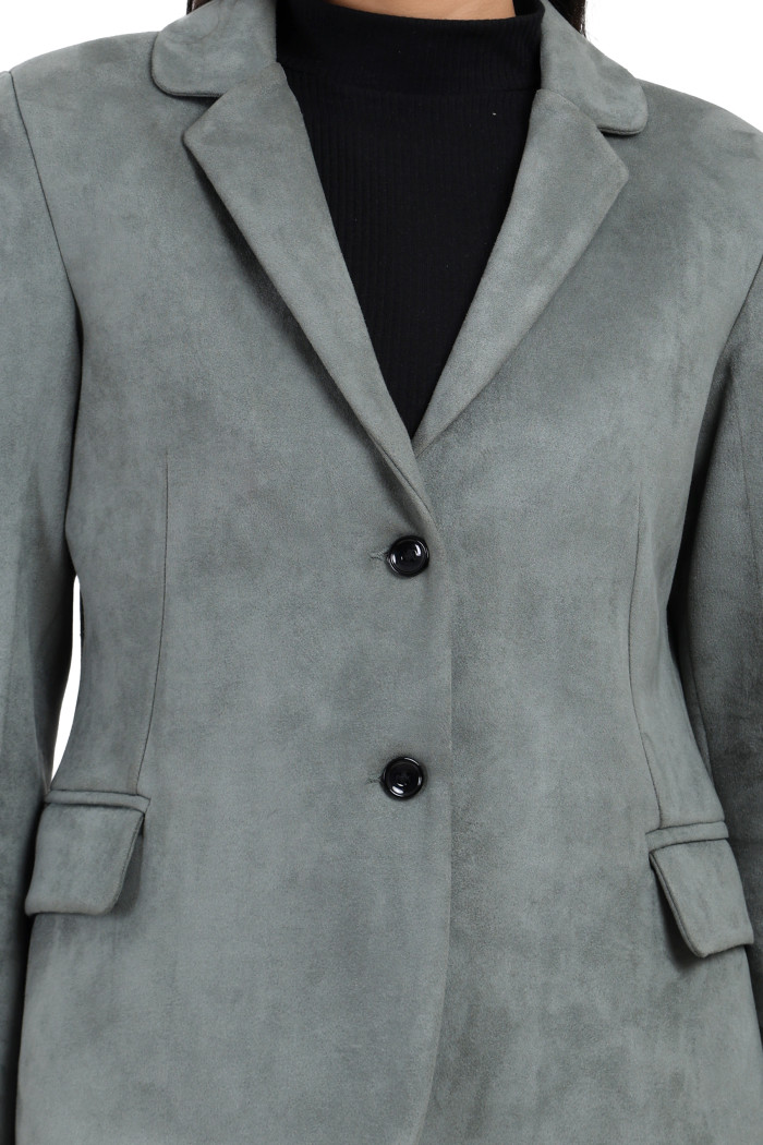 A cropped shot of a woman wearing Trufit’s short-length coat in pista with a lapel collar, side pockets and a button closure.