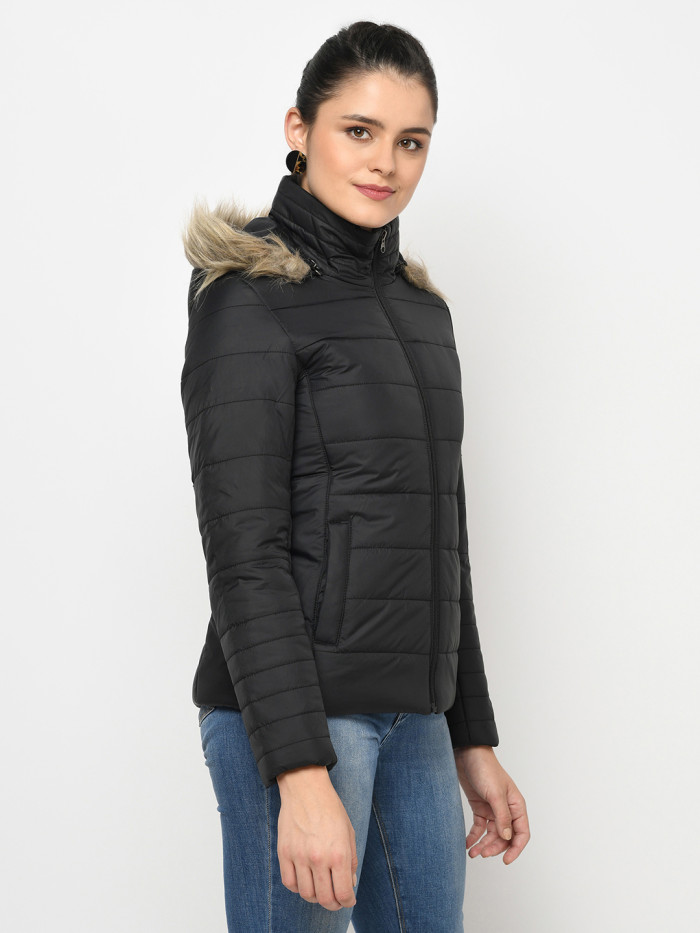 A left pose of a woman wearing a Black puffer jacket with a high neck, hood, zipper closure and pocket in hand designed for casual winter layering and comfort.