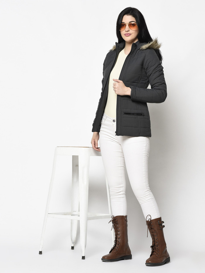 A woman wearing a Dark Grey Puffer jacket with a high neck, hood, zipper closure and pocket in hand designed for casual winter layering and comfort.