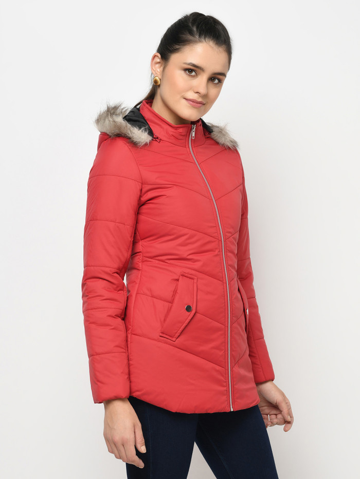 A left pose of a woman wearing a Red pufferjacket with a high neck, hood, zipper closure and pocket in hand designed for casual winter layering and comfort.